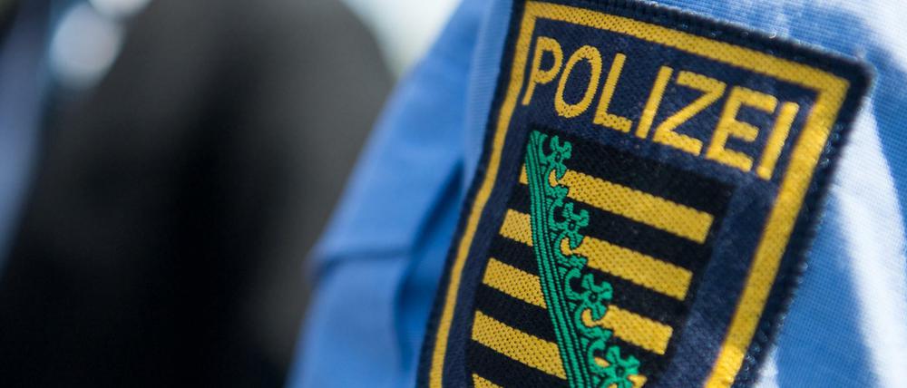 Das Logo der sächsischen Polizei ist an einer Polizeiuniform angebracht.