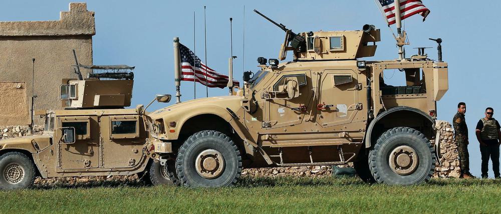 Soldaten stehen im syrischen Manbidsch neben Militärfahrzeugen über denen US-amerikanische Fahnen wehen. Am Donnerstag waren dort ein amerikanischer und ein britischer Soldat getötet worden.