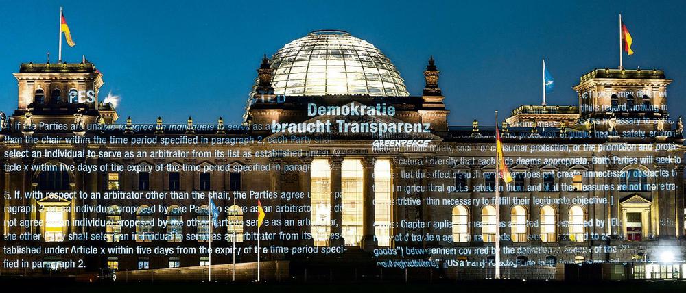 Aktivisten der Umweltorganisation Greenpeace projizieren am frühen Morgen des 02.05.2016 Teile des bisher geheimen Verhandlungstextes und den Schriftzug "Demokratie braucht Transparenz" auf die Fassade des Reichstagsgebäudes in Berlin, den Sitz des Deutschen Bundestages. 