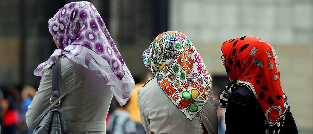 Türkischstämmige Frauen mit Kopftüchern stehen in der Kölner Fußgängerzone.