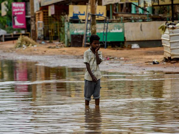Ein Junge steht in einer überfluteten Straße in Khartum im Sudan