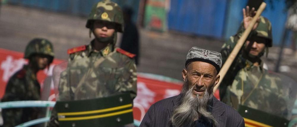 Ein Uigure geht in Ürümqi in der Unruheregion Xinjiang vorbei an chinesischen Sicherheitskräften.