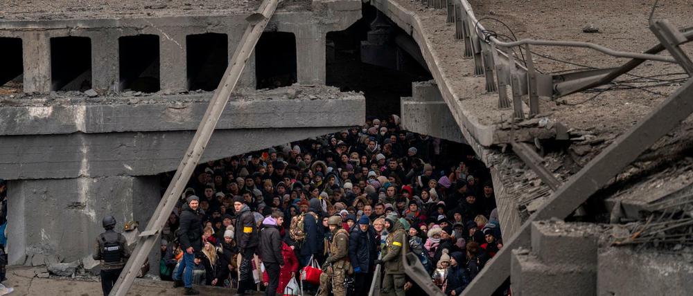 Ukrainer drängen sich unter einer zerstörten Brücke in Kiew