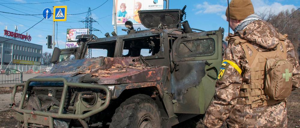 Ein ukrainischer Soldat inspiziert ein beschädigtes Militärfahrzeug in Charkiw.