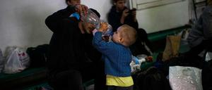 Oleander Kompaniets gibt seinem Sohn Dmytro, in einer Aufnahmestelle für ukrainische Binnenflüchtlinge aus einer Flasche zu trinken.