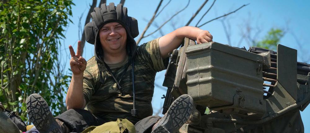 Ukraine, Donezk: Ein ukrainischer Soldat lächelt, während er das Siegeszeichen auf einem Panzer sitzend zeigt. 