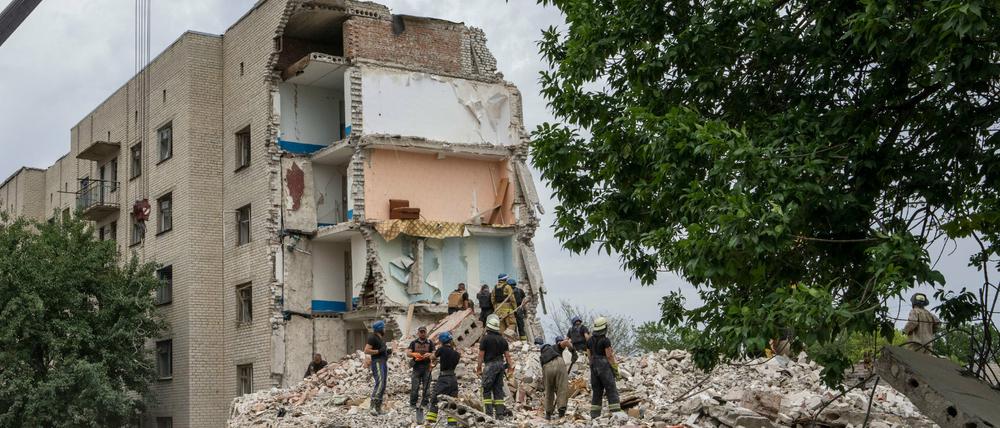 Rettungskräfte stehen nach einem Raketeneinschlag im ostukrainischen Tschassiw Jar in der Region Donezk auf den Trümmern eines Wohnblocks. 
