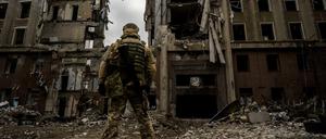 Ein ukrainischer Soldat steht vor einem zerstörten Gebäude .