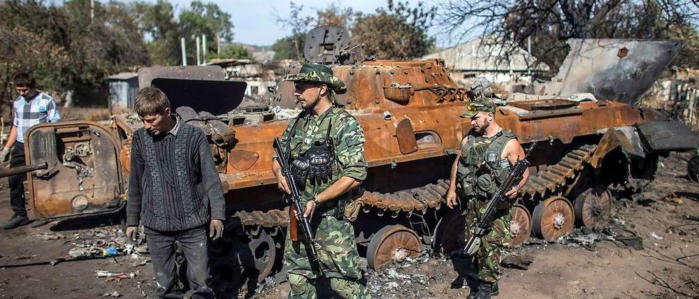 Prorussische Rebellen vor einem zerstörten ukrainischen Panzer.