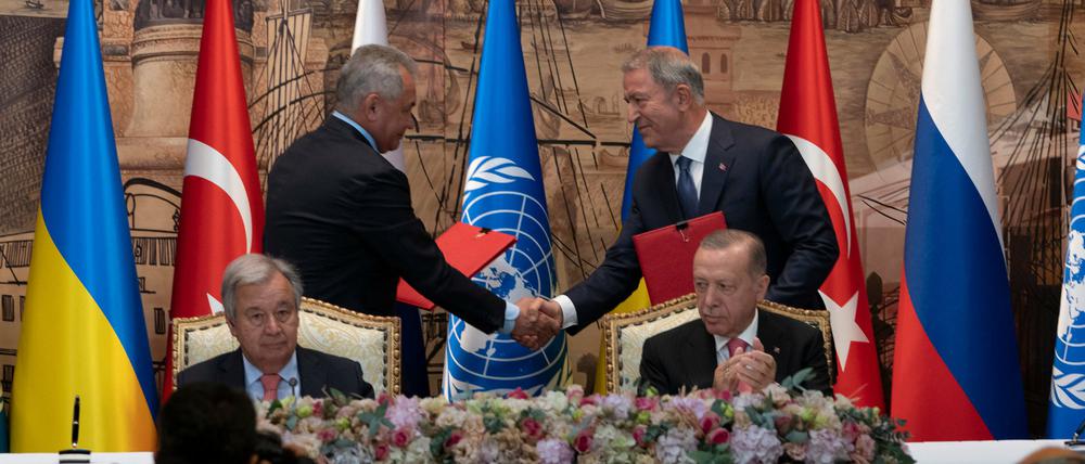 Antonio Guterres (vorn l), UN-Generalsekretär, und Recep Tayyip Erdogan (r), Präsident der Türkei, sitzen während einer Unterzeichnungszeremonie im Dolmabahce-Palast, während sich zwei Vertreter der Delegationen der Ukraine und Russlands die Hände reichen.