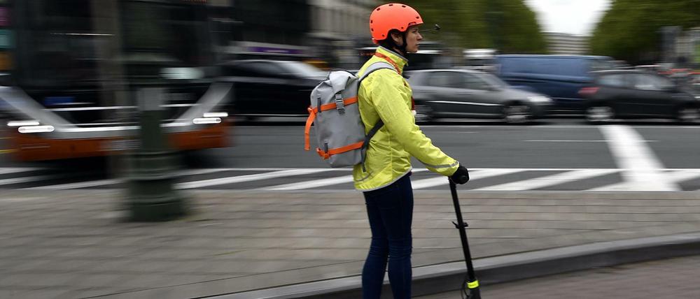 Ein Frau fährt mit einem E-Tretroller auf einem Fahrradweg in Brüssel. 