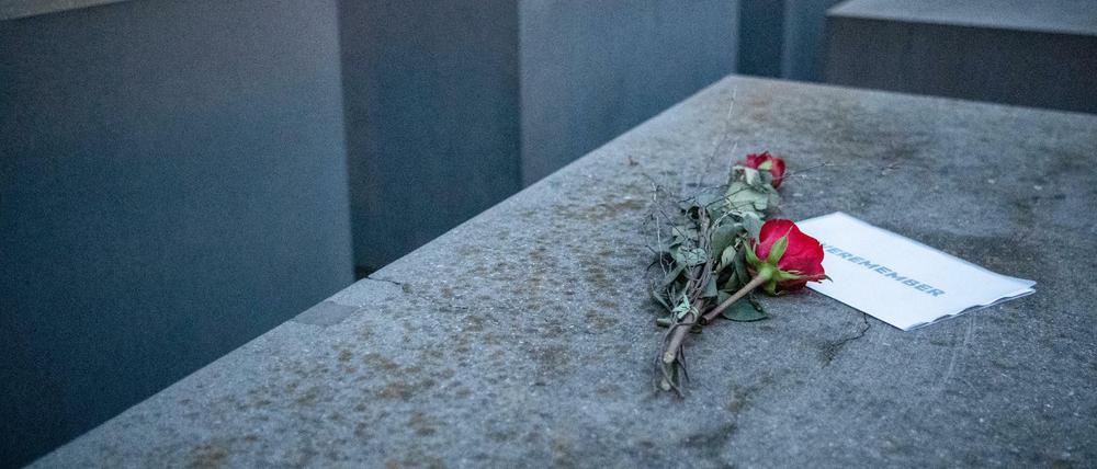 Rosen liegen mit einem Zettel, mit der Aufschrift "#weremember" am Holocaust-Mahnmal. 