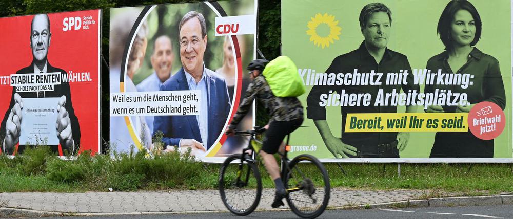 Ein Radfahrer fährt in Frankfurt am Main an Wahlplakaten mit den Spitzenkandidaten Olaf Scholz (SPD), Armin Laschet (CDU), Robert Habeck und Annalena Baerbock (Bündnis 90/Die Grünen) vorbei.
