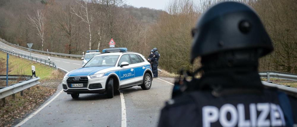 Polizeibeamte stehen an einer Absperrung an der Kreisstraße 22 rund einen Kilometer vom Tatort entfernt.