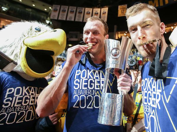 Endlich mal was Bissfestes. Luke Sikma (Mitte) feiert den Pokalsieg mit Niels Giffey (rechts) und dem Maskottchen. 