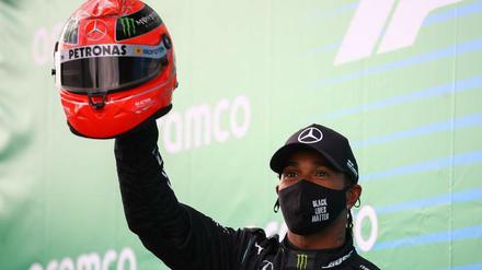 Roter Helm, schwarzes Outfit. Lewis Hamilton bei der Siegerehrung.