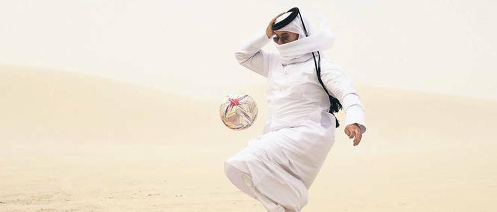 Ein Einwohner von Katar spielt mit einem Fußball.