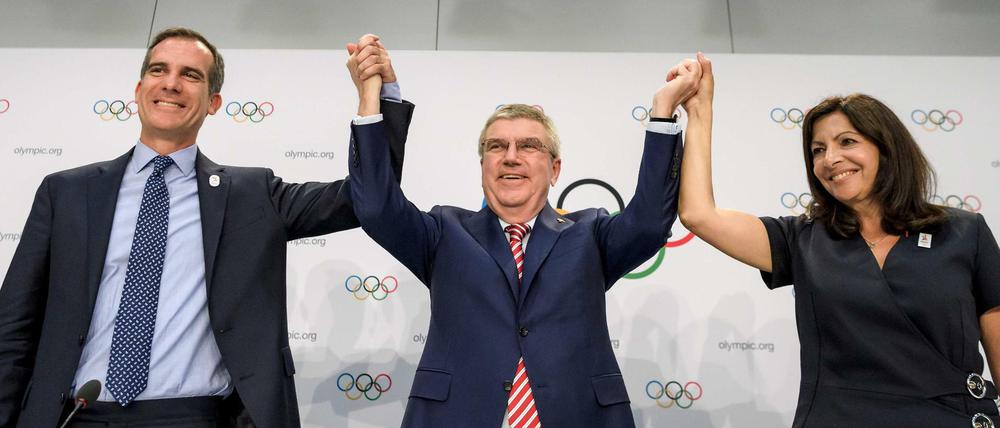 IOC-Präsident Thomas Bach in Jubelpose. Die Spiele 2024 und 2028 gehen nach Paris (rechts Bürgermeisterin Anne Hidalgo) und Los Angeles (links Eric Garcetti).