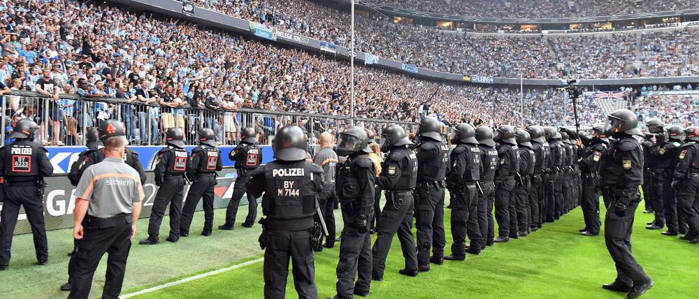 Polizisten sichern in der 80. Spielminute das Feld, nachdem Münchner Fans angefangen haben zu randalieren.