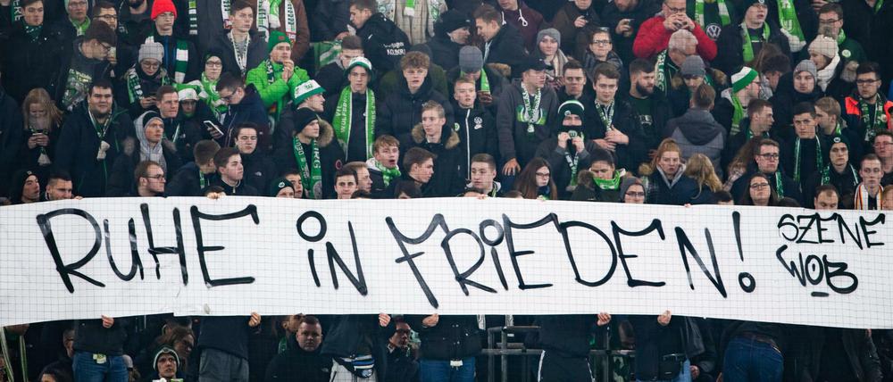 Fans des VfL Wolfsburg halten ein Plakat mit der Aufschrift "Ruhe in Frieden!". 