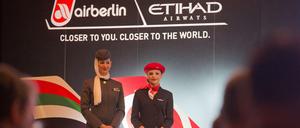 Eine Stewardess von Air Berlin (rechts) steht neben ihrer Kollegin von der Fluggesellschaft Etihad Airways im Dezember 2012 bei einer Pressekonferenz in Berlin. 