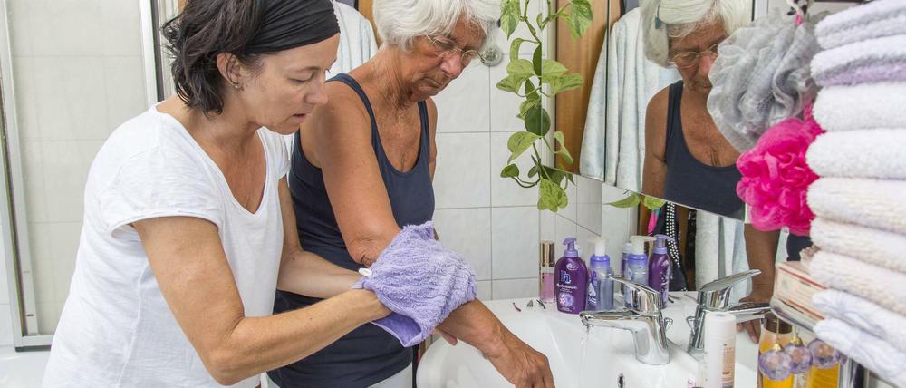 Eine Pflegerin hilft einer Seniorin beim Waschen.