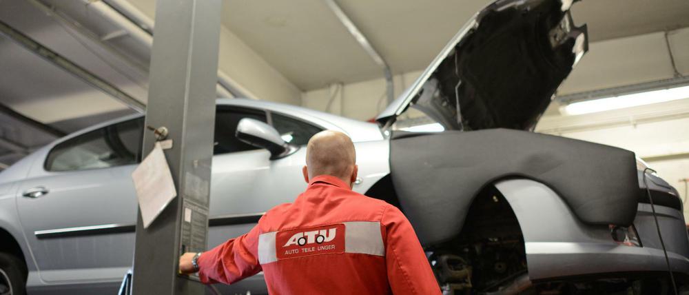 Ein Mitarbeiter der Werkstattkette ATU fährt in der Niederlassung am Frankfurter Ring in München (Bayern) ein Auto auf einer Hebebühne in die Höhe.