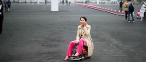 Made in China. Eine Chinesin demonstriert vor dem Messegelände ein selbst konstruiertes Minimobil.