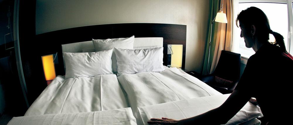 Ein Zimmermädchen macht in einem Hotel das Bett. 