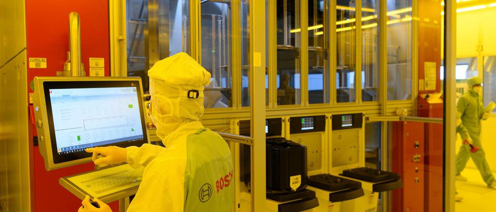 Ein Bosch-Mitarbeiter in der neuen Halbleiterfabrik im Reinraum an einer Maschine für die Bestückung von 300-Millimeter-Wafern. 