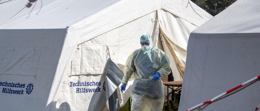 Zelte gegen Corona: Ein Mitarbeiter vom Klinikum Bremen-Ost läuft in Schutzkleidung durch die Zelte der Corona-Ambulanz, in denen Patienten auf den Corona-Test warten. 