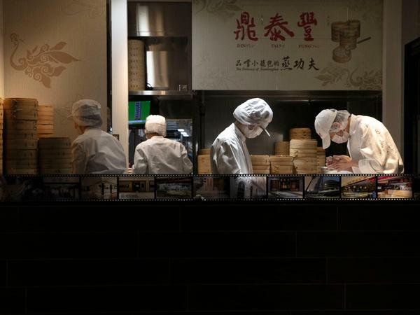 Köche tragen einen Mundschutz, während sie Knödel in einem Restaurant in Tokio zubereiten. 