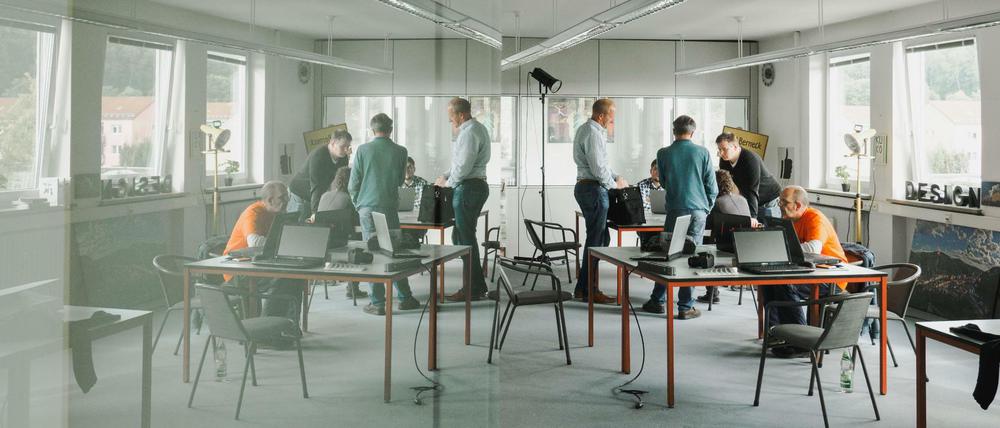 Mitarbeiter unterhalten sich an einem Arbeitstisch in einem Coworking-Space. 