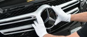 Ein Mitarbeiter von Mercedes-Benz bringt im Werk den Stern an einem Auto der C-Klasse an (Symbolbild).
