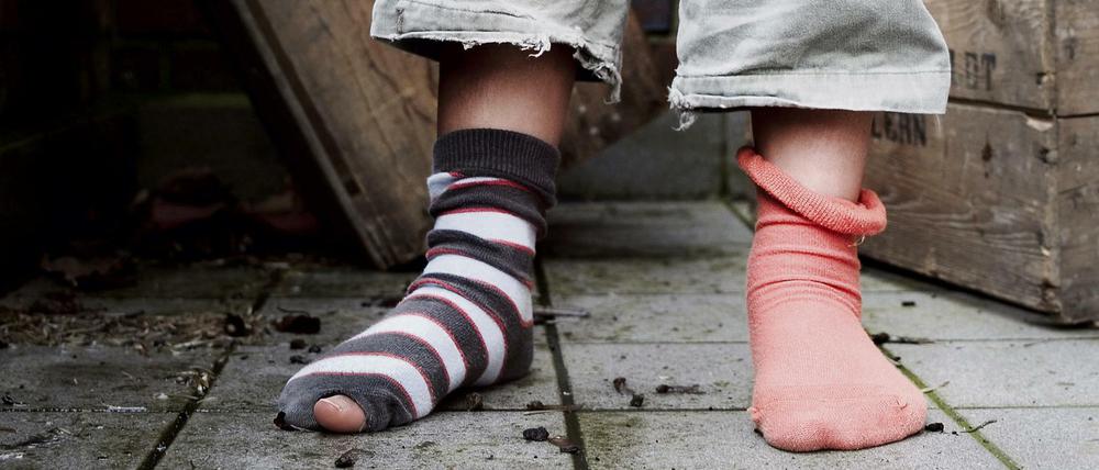 Ein zehn Jahre altes Mädchen steht in abgetragener Kleidung ohne Schuhe in einem Hinterhof.