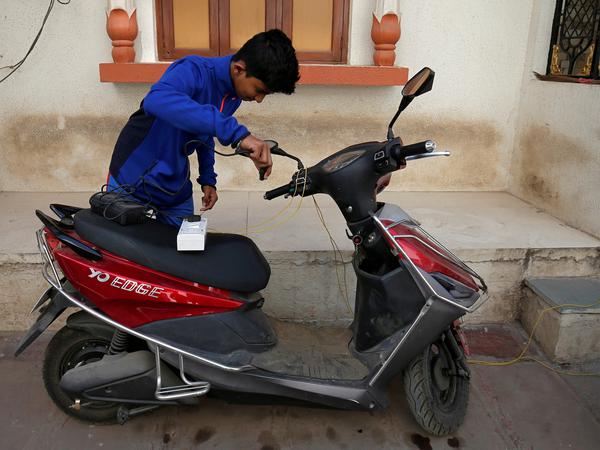 Ein junge im indischen Ahmedabad bereitet seinen E-Scooter zur Aufladung vor.
