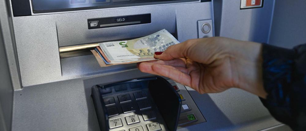 Eine Frau hebt am Bankautomaten Geld ab