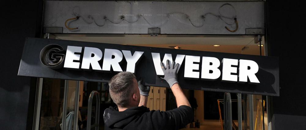 Ein Monteur hängt ein Schild an einer geschlossenen Filiale der Modemarke "Gerry Weber" ab. 