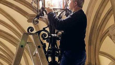 Auftritt. Während Hamburgs Bürgermeister am Donnerstag den Stromnetz-Deal vorstellte, tauschte ein Haustechniker in der Empfangshalle des Rathaus eine Lampe aus. Foto: dpa