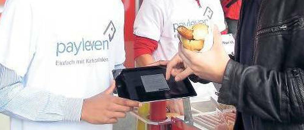 Ungewohnt. Der Verkäufer hält dem Kunden ein Tablet zur Unterschrift hin, damit dieser sein Ein-Euro-Würstchen bezahlen kann. Zuvor hat er seine Kreditkarte durch einen kleinen Plastikaufsatz an dem mobilen Computer gezogen. 