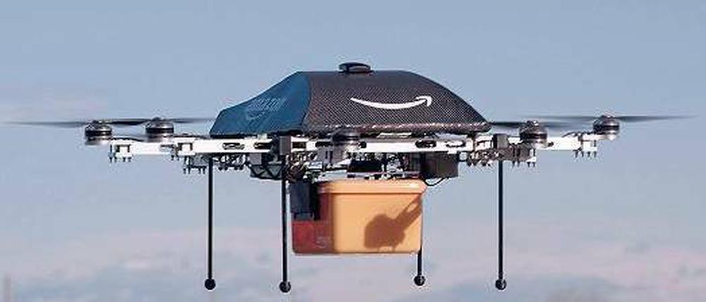 Zustellung ohne Bote. Für Amazon liegt die Zukunft der Logistik in der Luft. Der „Octocopter“, so genannt wegen der acht Motoren, trägt das Logo des Konzerns. Der geschwungene Pfeil soll ein Lächeln symbolisieren. Unten hängt eine gelbe Box für die bestellte Ware. Foto: dpa