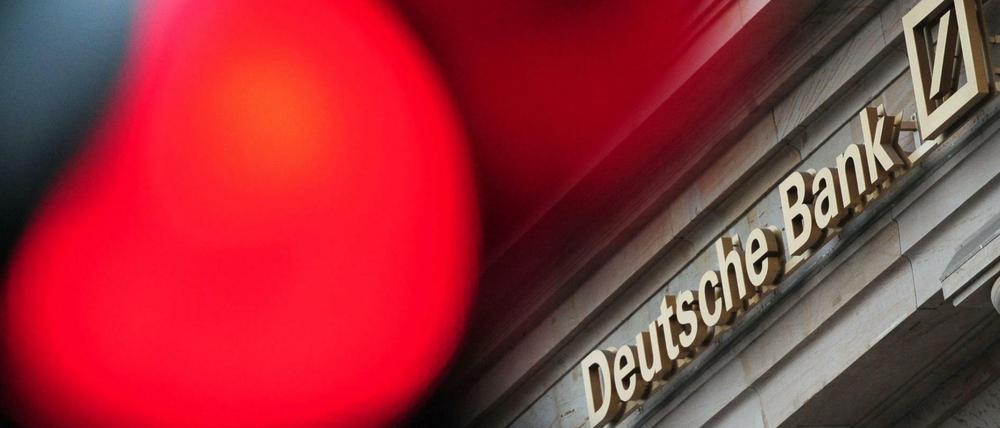 Eine rote Ampel leuchtet in Frankfurt am Main vor einer Filiale der Deutschen Bank.