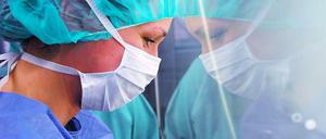 Im Unfallkrankenhaus Berlin blickt eine Krankenschwester mit Mudschutz durch eine Scheibe in den Operationssaal.