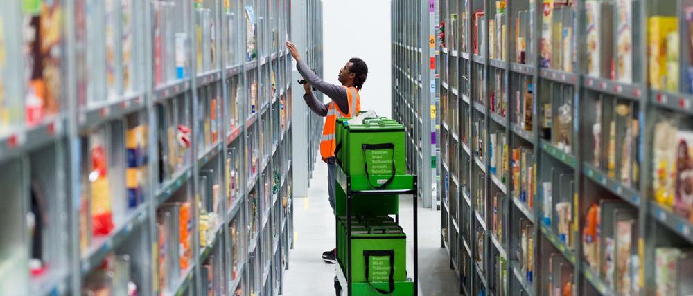 Ein Mitarbeiter des Lebensmittellieferdienstes Amazon Fresh im Depot der Firma in Berlin die bestellten Waren in eine Transporttasche. Amazon Fresh war Anfang Mai in Berlin und Potsdam mit einem Sortiment von rund 85.000 Artikeln gestartet.