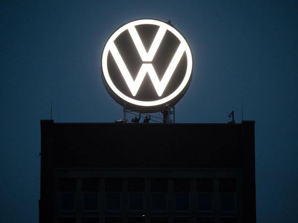 Arbeiter enthüllen das neue Logo von Volkswagen auf dem Markenhochhaus am VW Werk.