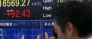 Ein Passant läuft am Freitag an Bildschirmen der Tokioter Börse vorbei. In Japan haben rote Ziffern eine positive Bedeutung.