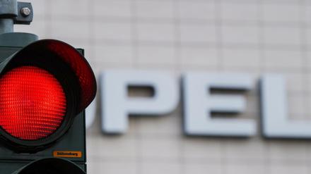 Eine rote Ampel leuchtet vor dem Opel-Schriftzug in Rüsselsheim.