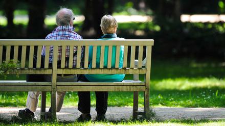 Zwei Rentner sitzen im Schatten des Schlossparks Charlottenburg auf einer Bank.