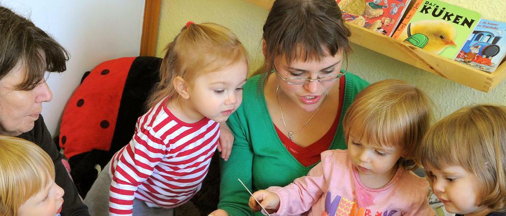 In einer Leipziger Kindertagesstätte schauen die Kinder mit einer Logopädin und einer Erzieherin Bücher an.