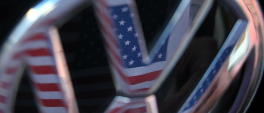 Eine US-amerikanische Flagge spiegelt sich im Logo eines Volkswagens. 